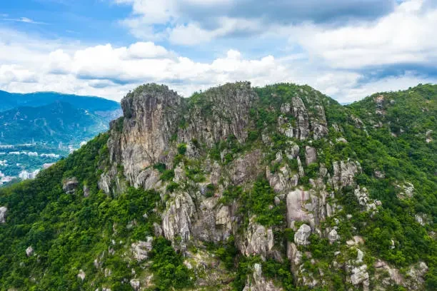 Lion Rock hillside with steep grey rock faces surrounded by dense green vegetation in Hong Kong.